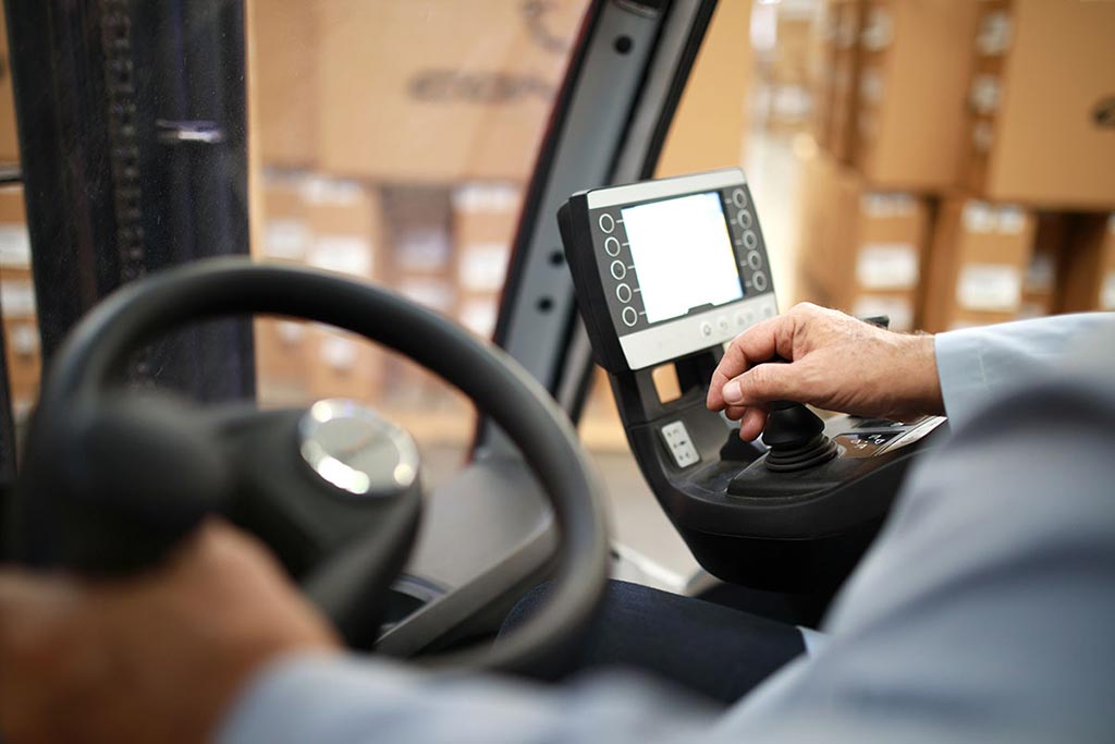 Close up of operator driving electric forklift.